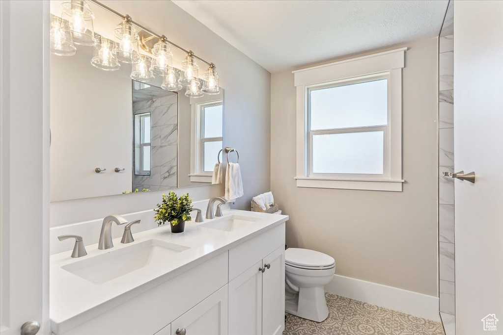 Full bath featuring double vanity and plenty of natural light