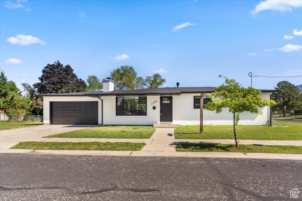 Ranch-style home featuring a chimney, driveway, and an attached garage