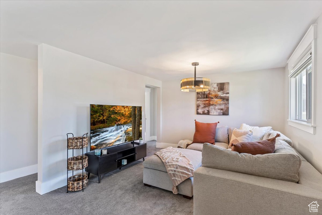 Carpeted living room featuring a chandelier and baseboards