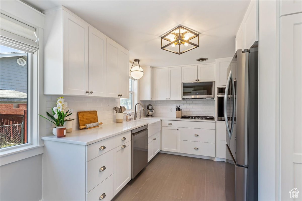 Kitchen featuring stainless steel appliances, backsplash, and white cabinetry