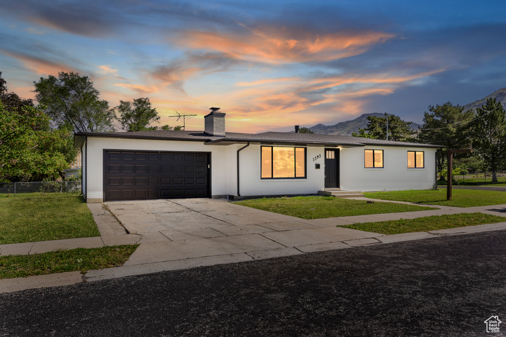 Ranch-style house featuring a garage, concrete driveway, a front lawn, and a chimney