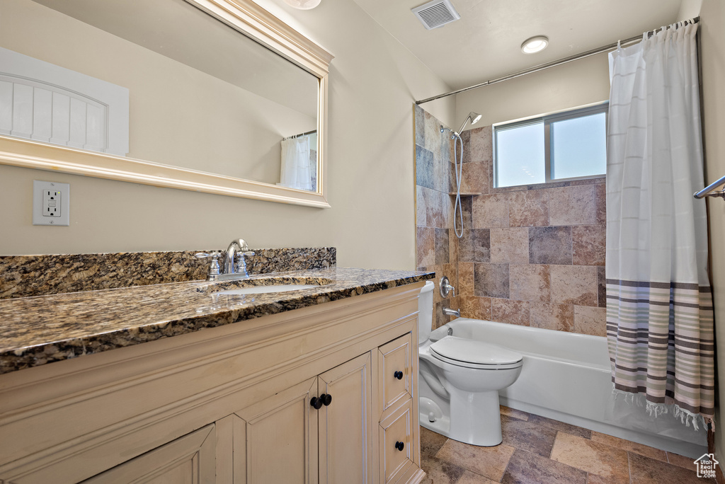 Bathroom with vanity, stone tile flooring, and shower / bath combination with curtain