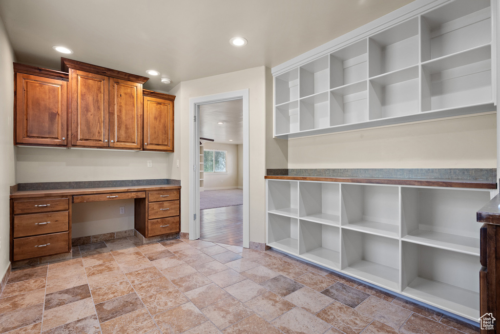 Unfurnished office featuring built in study area, stone tile flooring, and recessed lighting