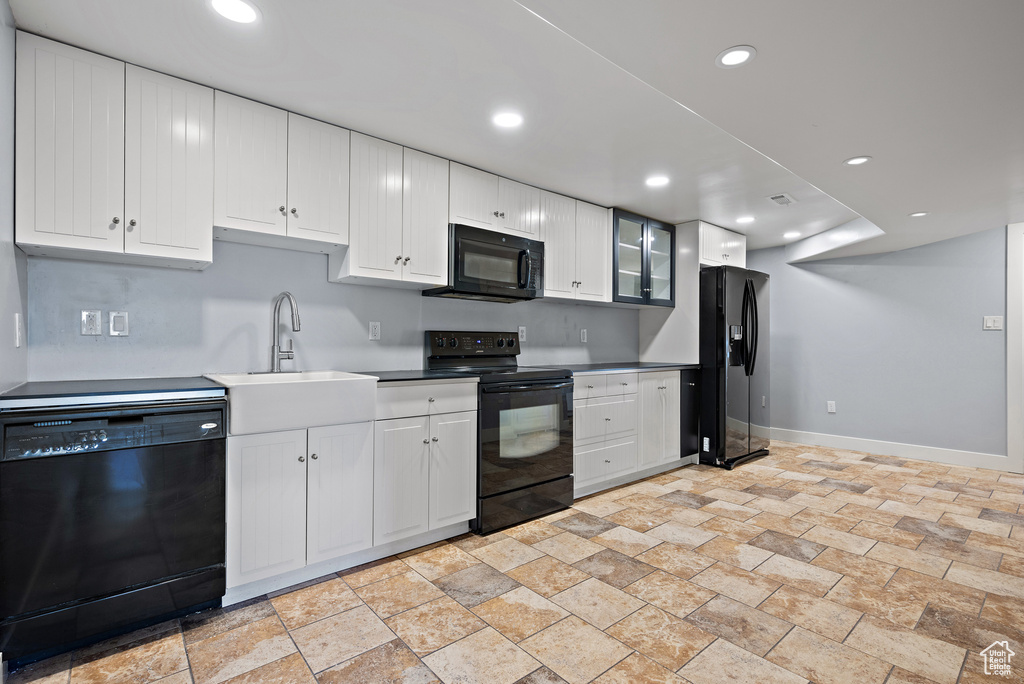 Kitchen featuring black appliances, stone tile flooring, white cabinets, and recessed lighting