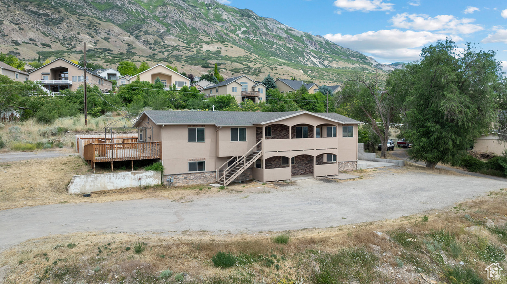 View of front of home featuring stucco siding, stone siding, a deck with mountain view, and stairway