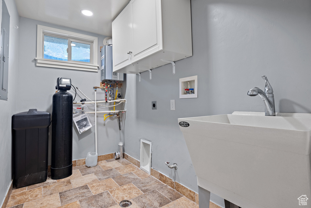 Laundry area featuring cabinet space, water heater, electric dryer hookup, light stone finish floors, and hookup for a washing machine