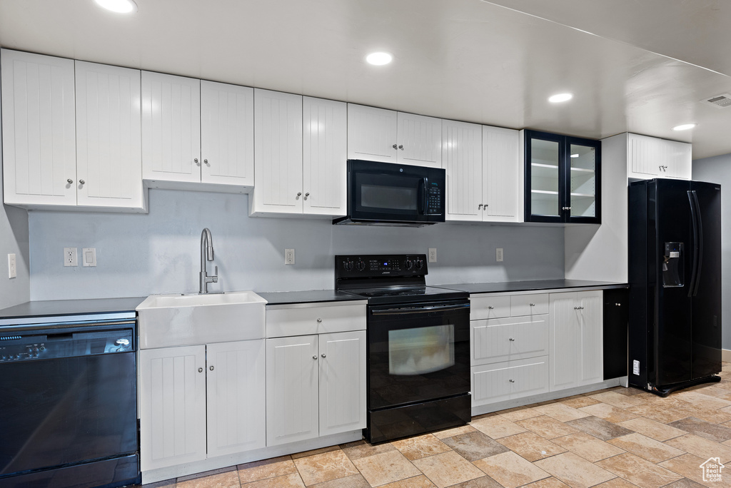 Kitchen featuring black appliances, light stone finish flooring, white cabinetry, and recessed lighting
