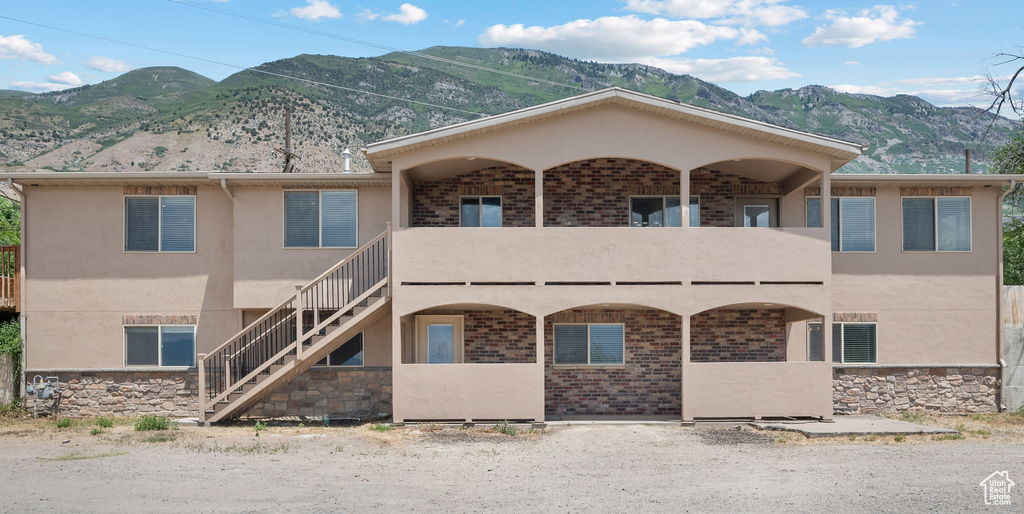 View of front of property with a mountain view, stairway, a balcony, and stucco siding