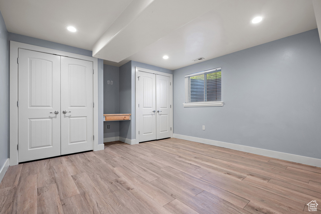 Unfurnished bedroom featuring multiple closets, light wood-style flooring, and recessed lighting