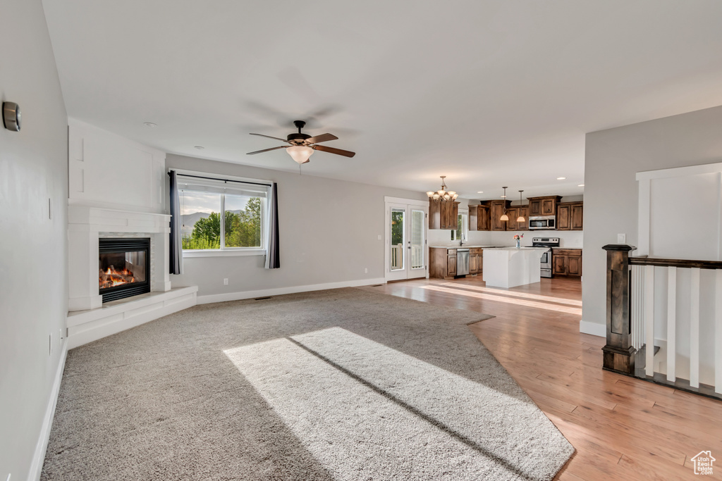 Unfurnished living room with plenty of natural light, ceiling fan, a glass covered fireplace, recessed lighting, and a chandelier