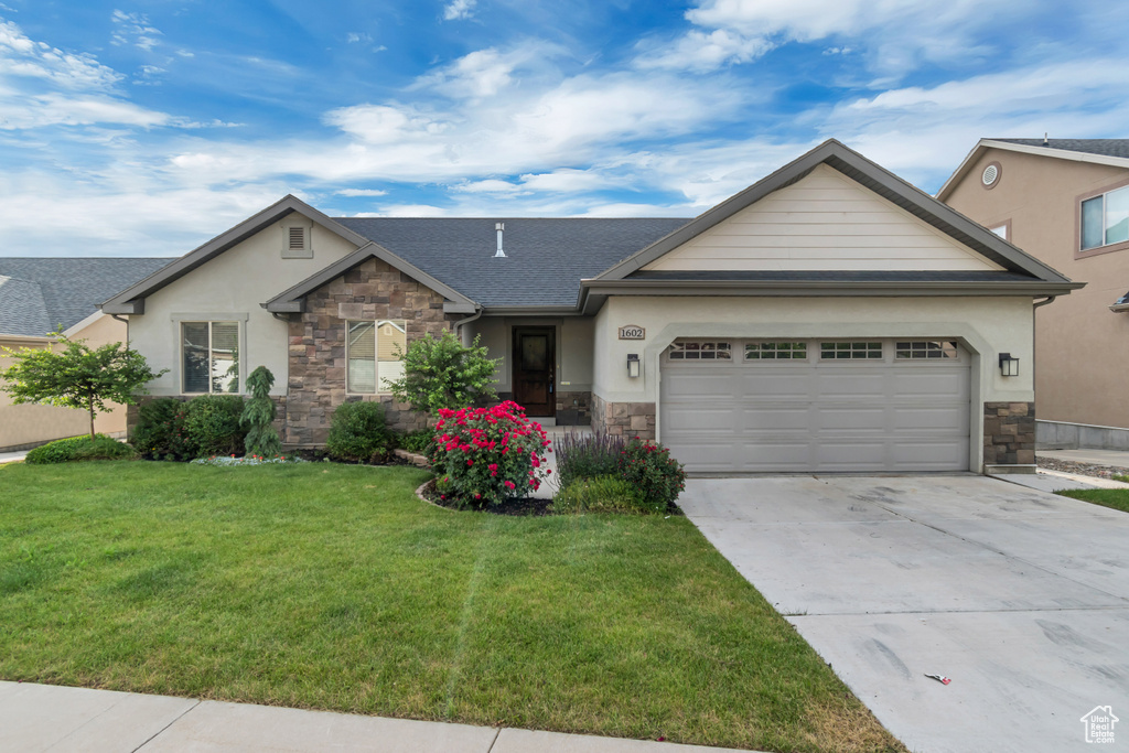 Single story home featuring stone siding, an attached garage, driveway, and a front yard