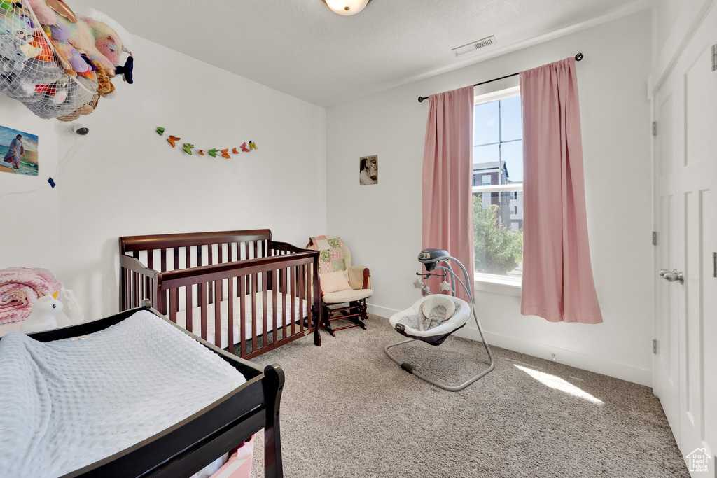 Bedroom featuring carpet flooring and a crib