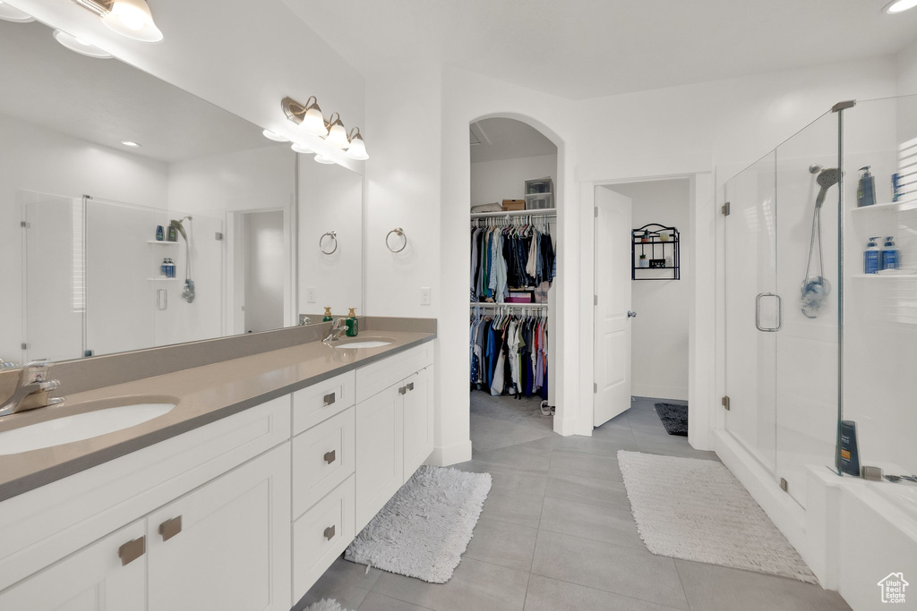 Full bath with a stall shower, double vanity, a walk in closet, tile patterned flooring, and recessed lighting