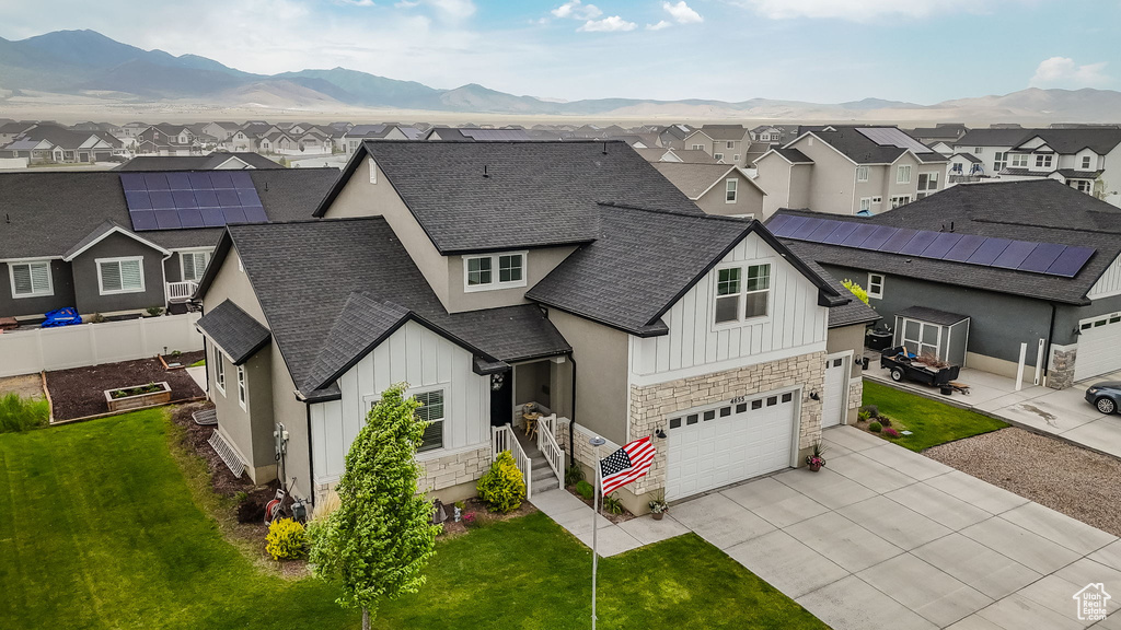 View of front facade featuring board and batten siding, a residential view, stone siding, and concrete driveway