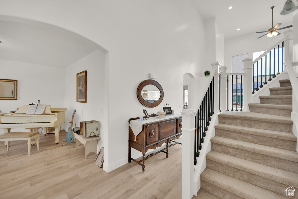 Staircase featuring arched walkways, ceiling fan, wood finished floors, and recessed lighting