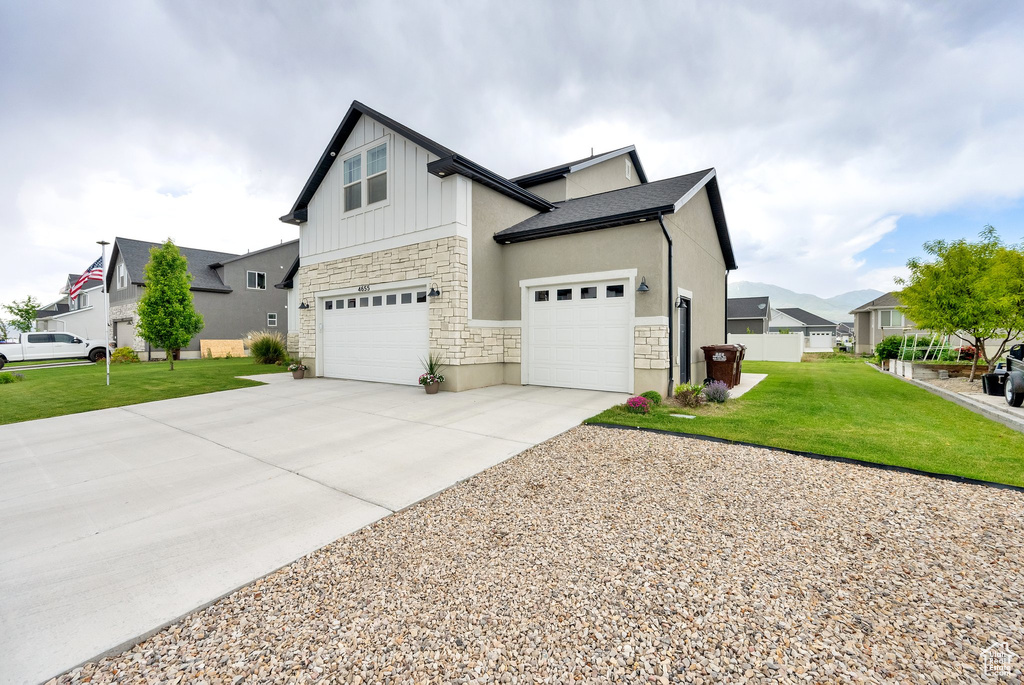 View of side of home featuring stone siding, board and batten siding, concrete driveway, and a garage