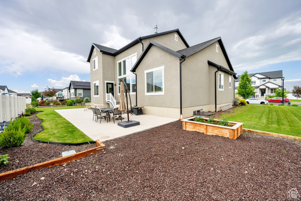 Rear view of house featuring a patio area, a residential view, stucco siding, and a vegetable garden