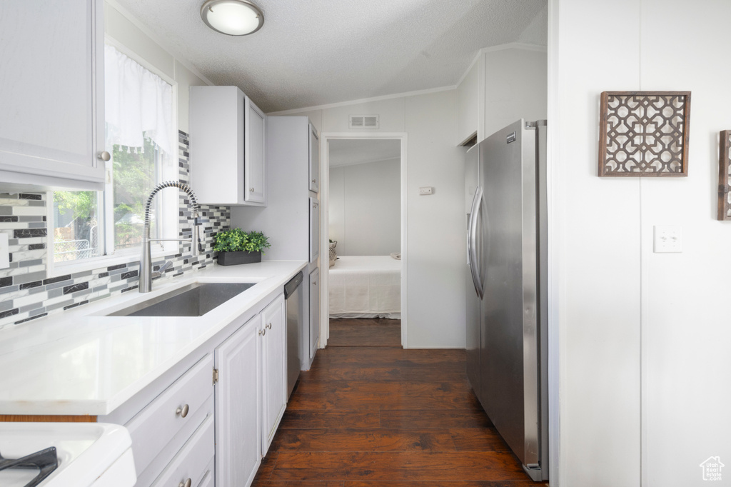 Kitchen with a sink, stainless steel appliances, dark wood-type flooring, tasteful backsplash, and light countertops