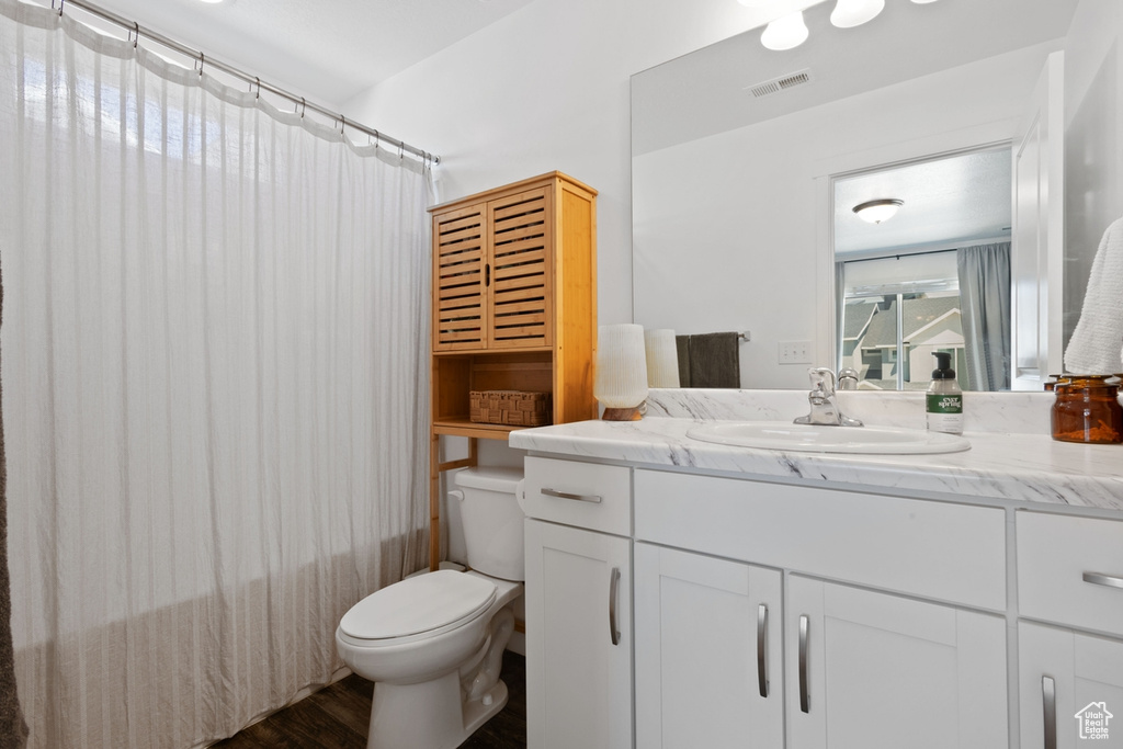 Bathroom featuring vanity, shower / bathtub combination with curtain, and wood finished floors