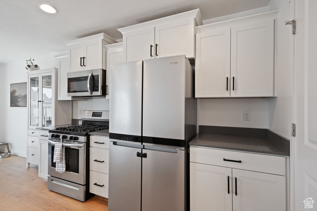 Kitchen featuring stainless steel appliances, white cabinets, light wood-style flooring, and recessed lighting