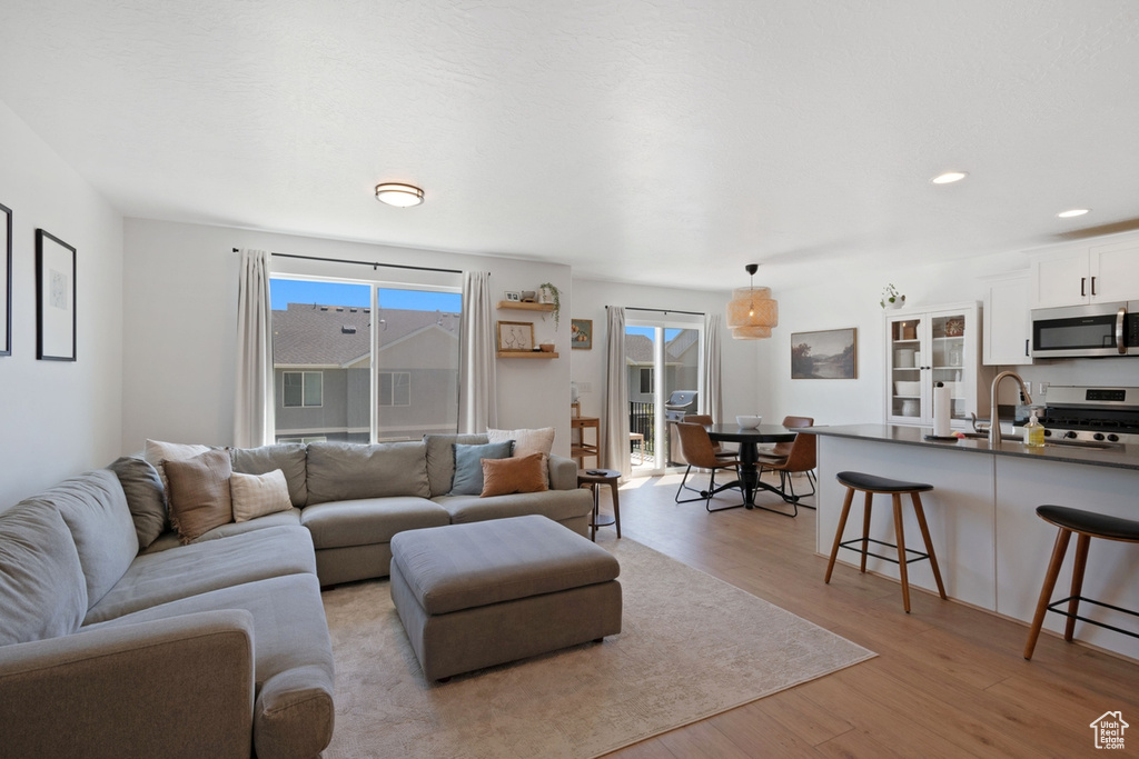 Living area with light wood finished floors and recessed lighting
