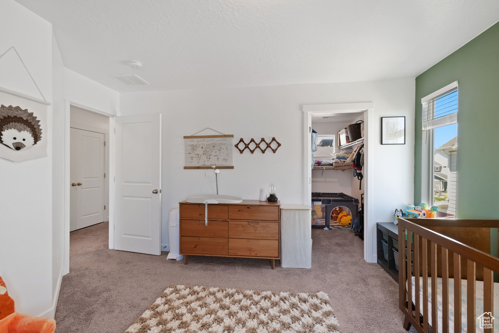 Bedroom with light colored carpet, a walk in closet, and a closet