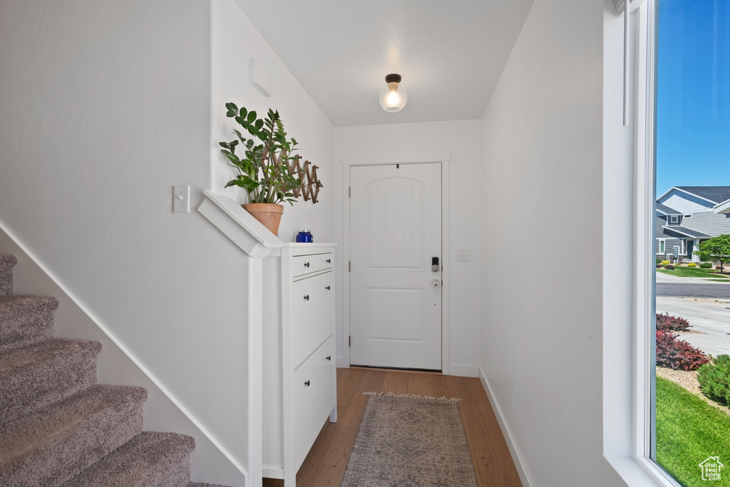 Doorway to outside featuring light wood-style flooring and stairway