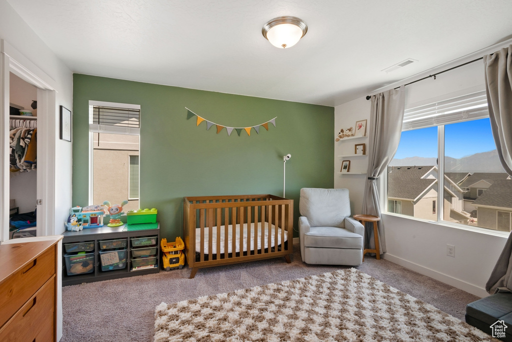 Carpeted bedroom with baseboards and a crib