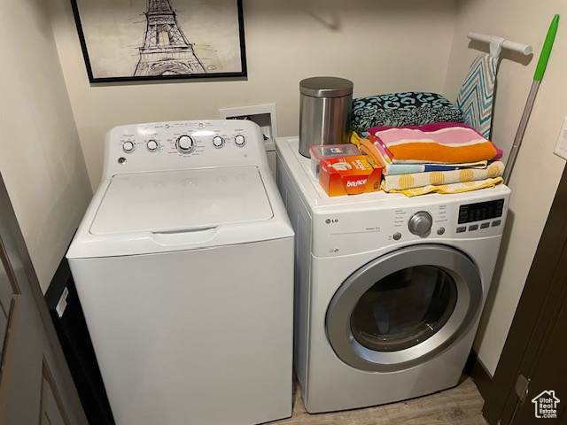 Washroom with independent washer and dryer and light wood-type flooring