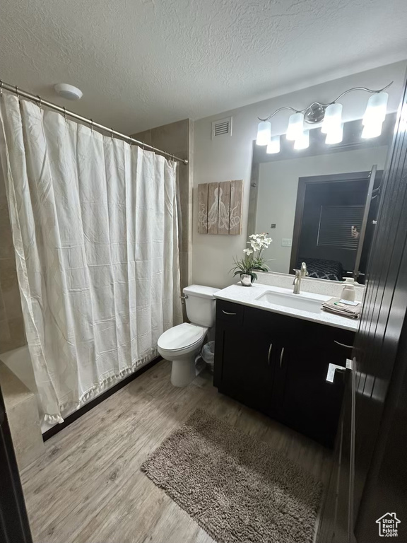 Bathroom featuring wood finished floors, vanity, a textured ceiling, and shower / bath combo