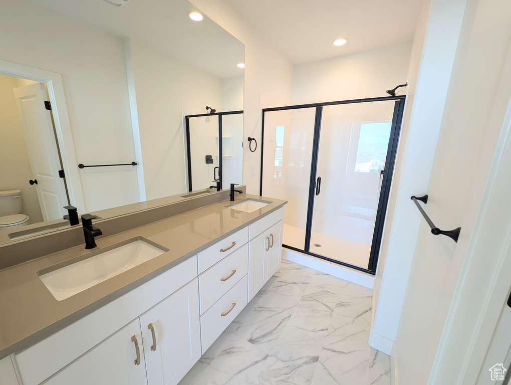 Full bathroom featuring marble finish floors, double vanity, a stall shower, and recessed lighting