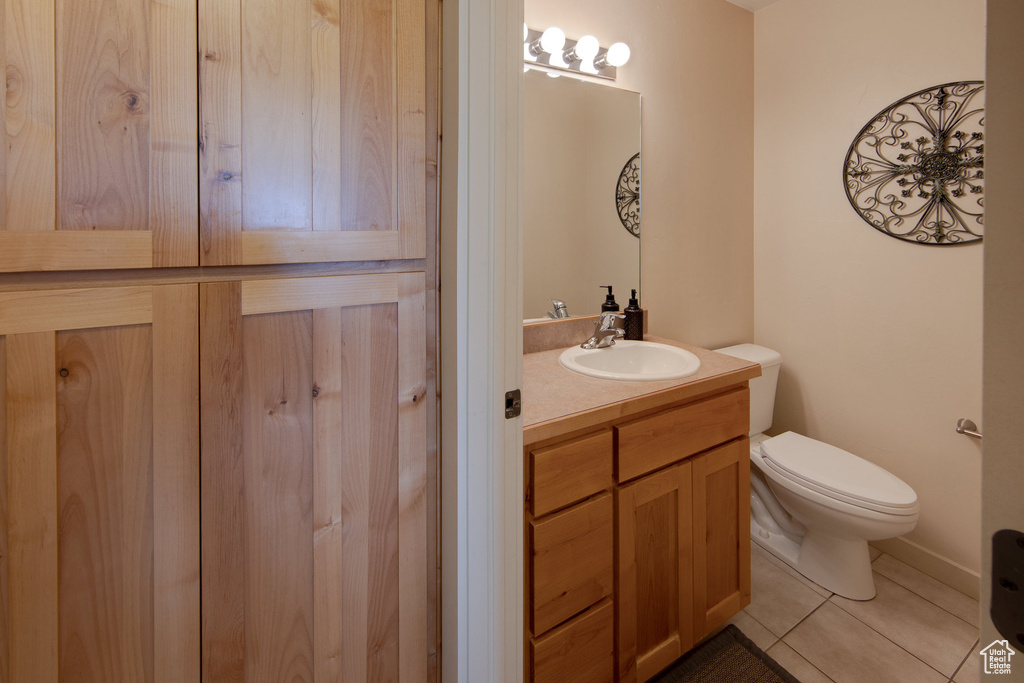Half bath with vanity, toilet, and tile patterned flooring
