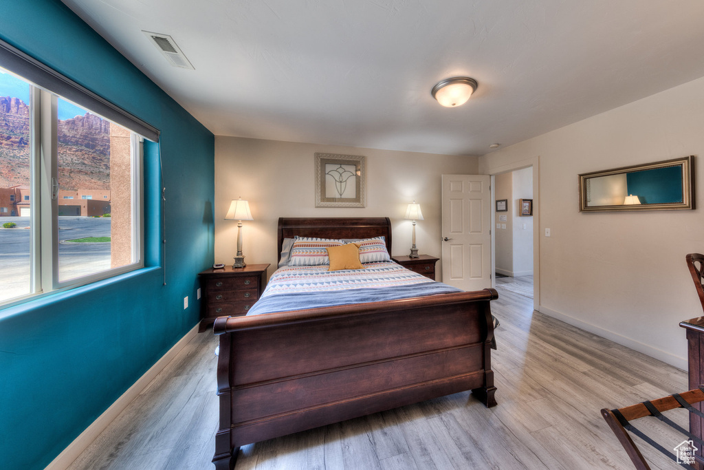 Bedroom featuring multiple windows, light wood finished floors, and baseboards