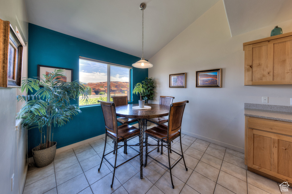 Dining area with vaulted ceiling, baseboards, and light tile patterned floors