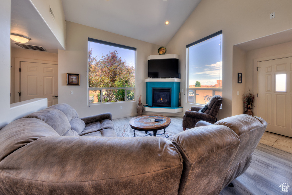 Living area featuring a glass covered fireplace, recessed lighting, wood finished floors, and high vaulted ceiling