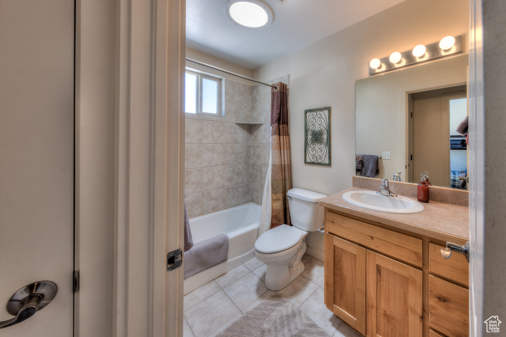 Full bathroom featuring toilet, tile patterned flooring, shower / tub combo with curtain, and vanity