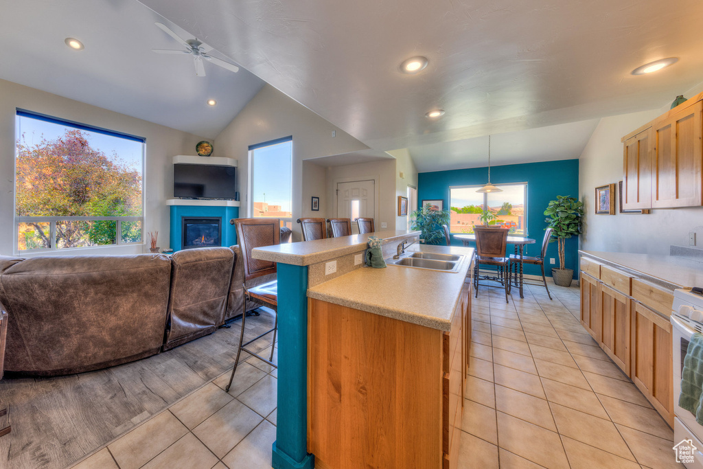 Kitchen featuring open floor plan, a sink, light countertops, a kitchen breakfast bar, and recessed lighting