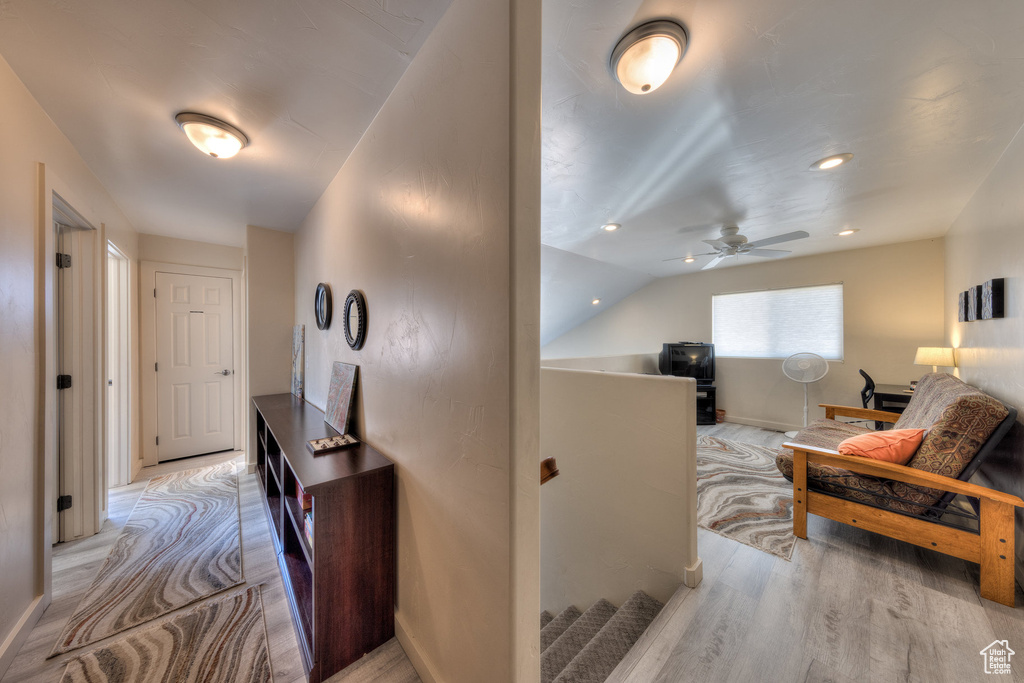 Hallway with wood finished floors, an upstairs landing, vaulted ceiling, and baseboards