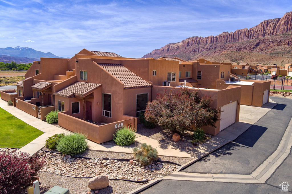 Pueblo-style house featuring stucco siding, a mountain view, a tiled roof, and a residential view