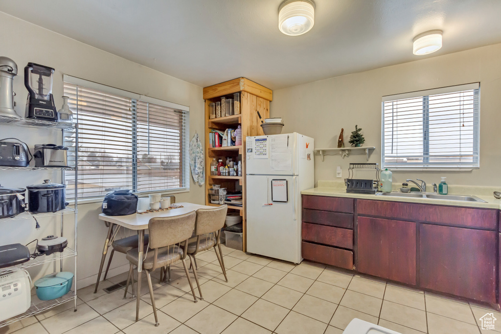 Kitchen with freestanding refrigerator, open shelves, light countertops, and light tile patterned floors