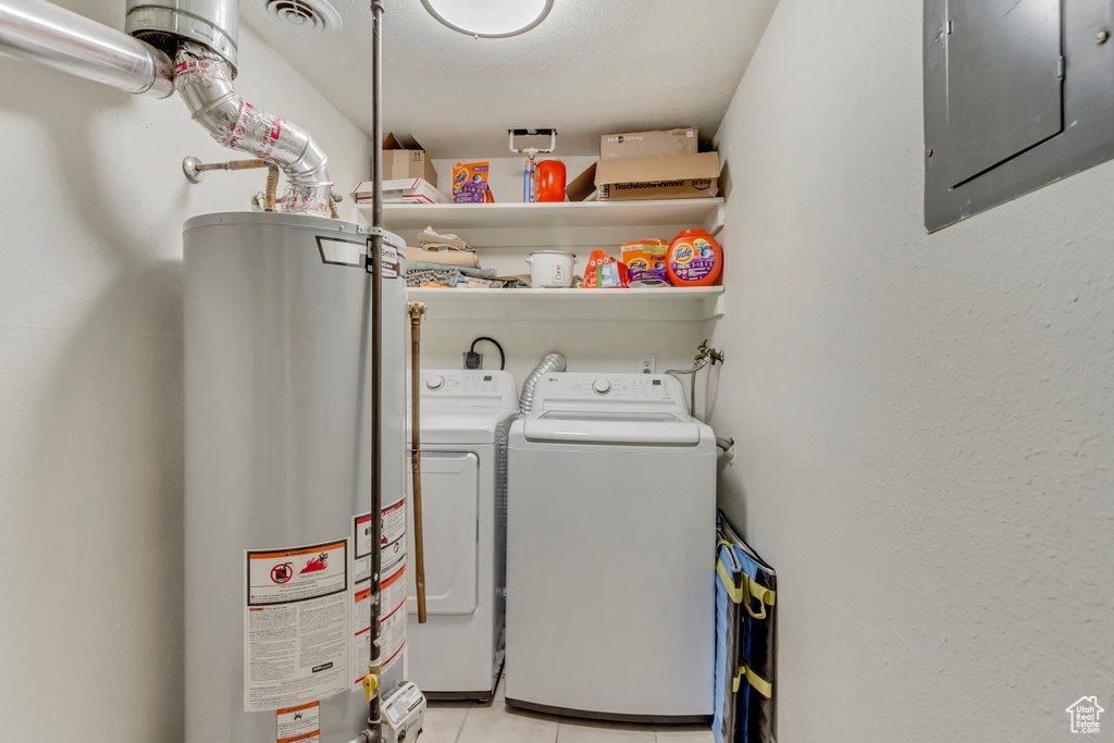 Washroom featuring electric panel, gas water heater, washer and clothes dryer, and light tile patterned flooring