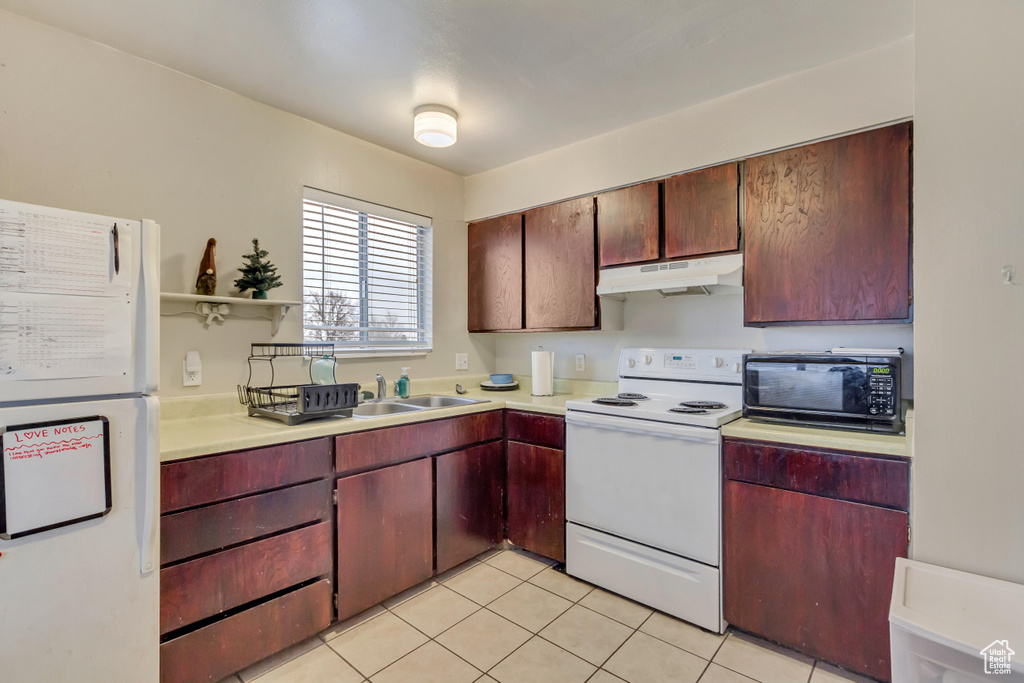 Kitchen with white appliances, under cabinet range hood, light countertops, light tile patterned flooring, and open shelves