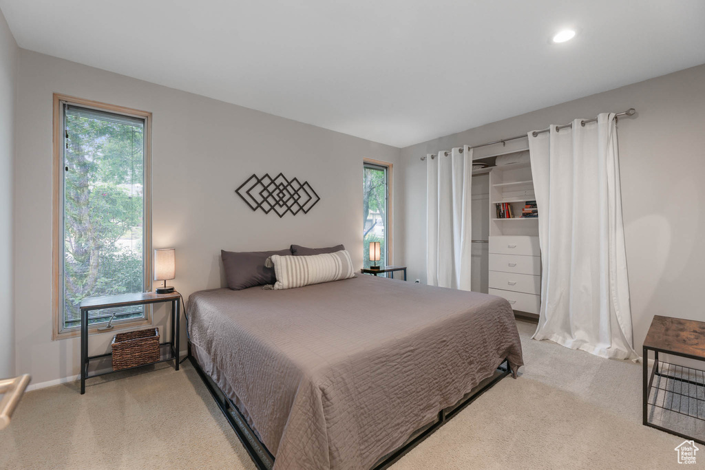 Bedroom with light colored carpet, multiple windows, and recessed lighting