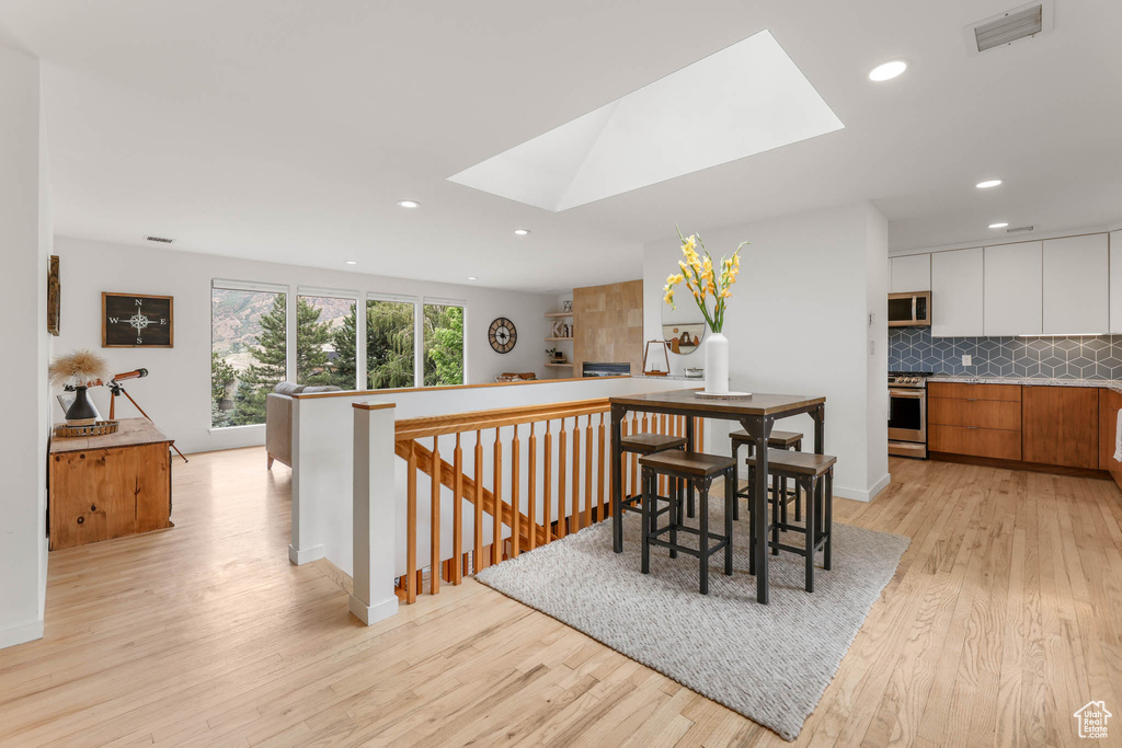 Dining space featuring a skylight, light wood-style floors, and recessed lighting