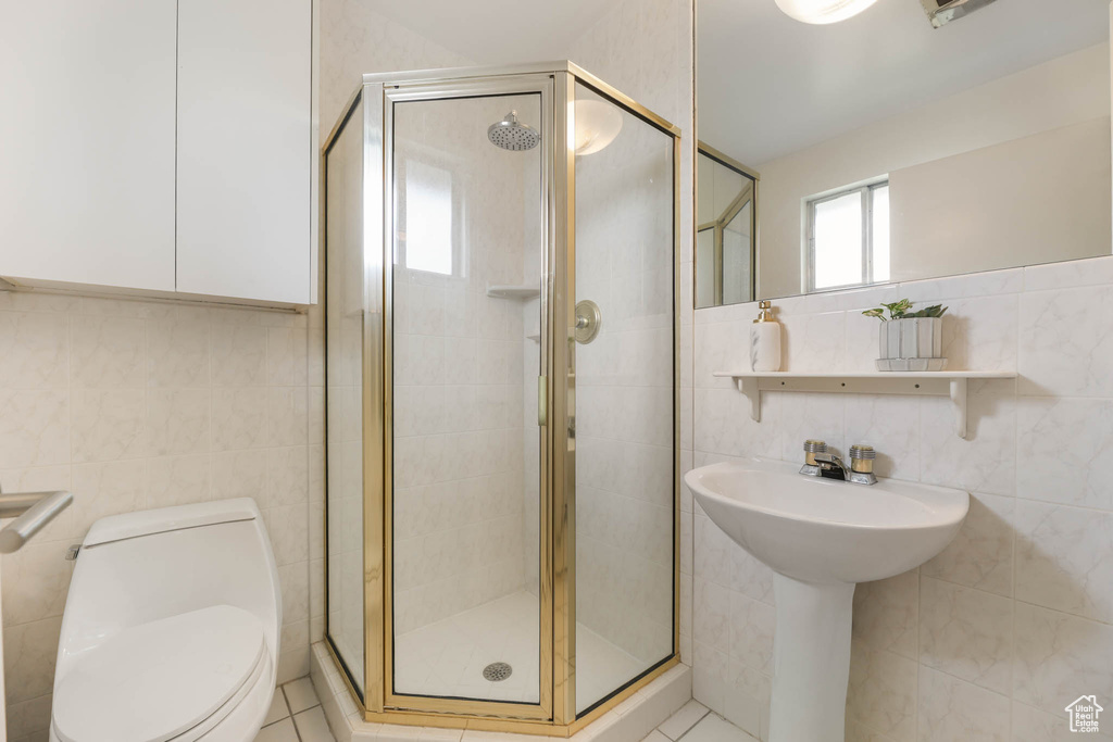 Full bathroom featuring tile walls, a shower stall, and tile patterned flooring