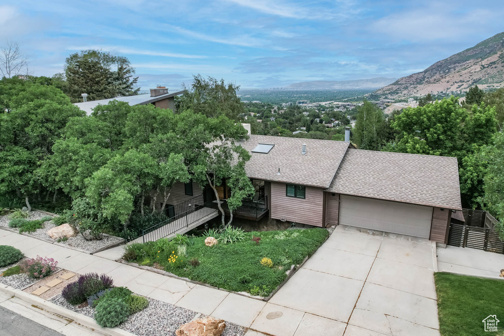View of front of property with roof with shingles, a garage, driveway, and a mountain view