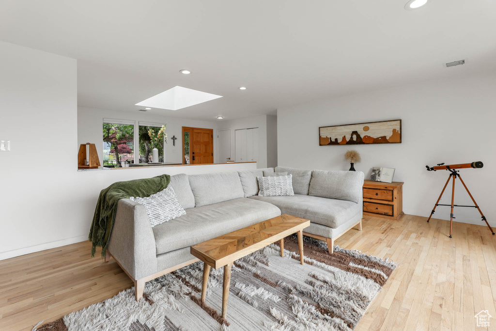 Living area featuring light wood-type flooring, a skylight, and recessed lighting