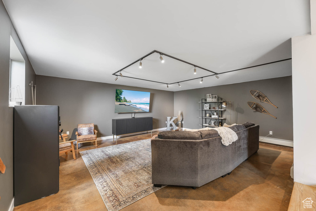 Living room with a baseboard radiator, concrete flooring, and rail lighting