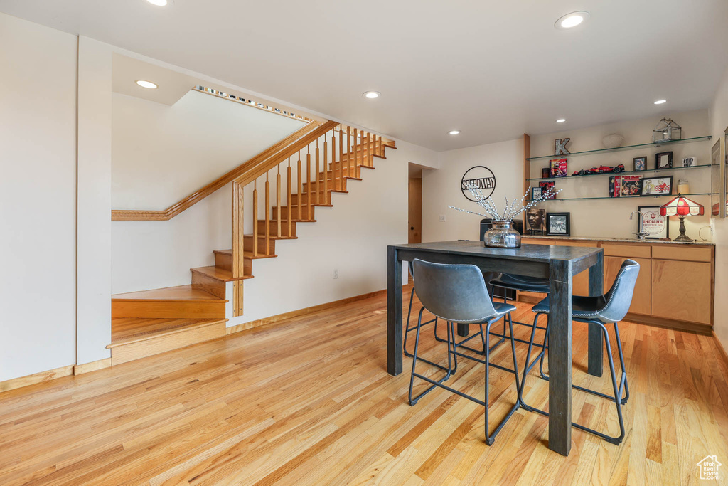 Dining space featuring recessed lighting, stairs, light wood-style flooring, and bar