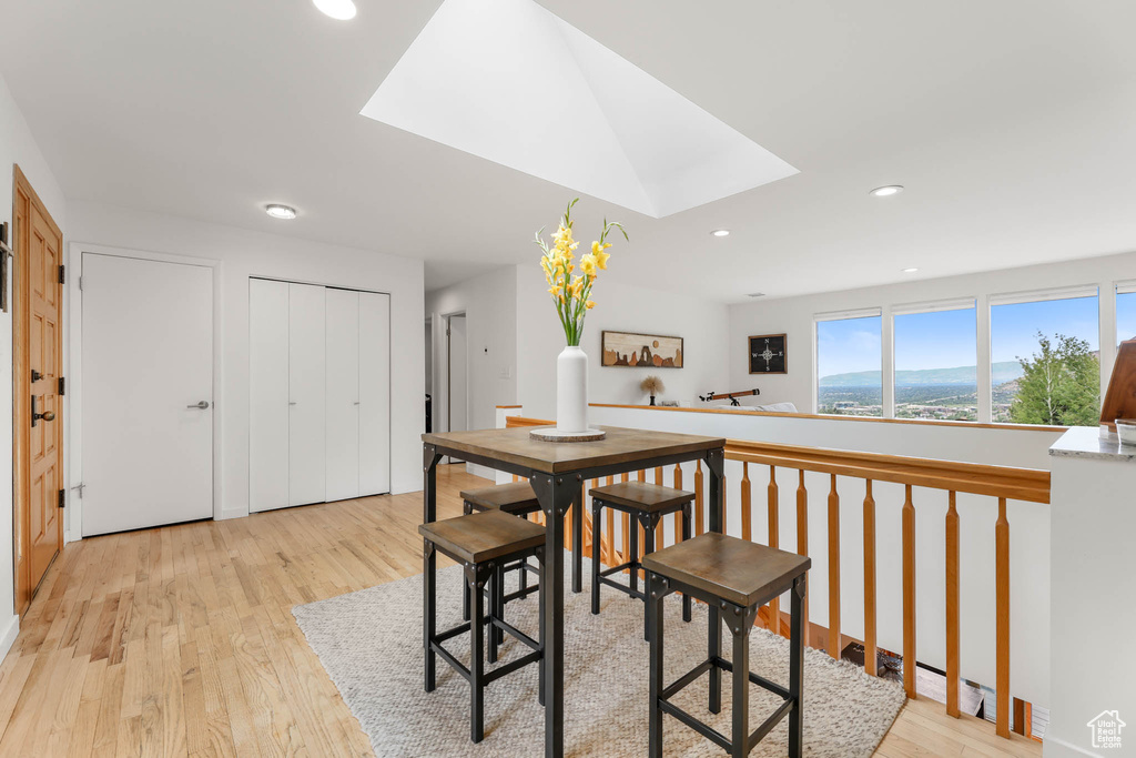 Dining room with light wood-style floors, a skylight, and recessed lighting